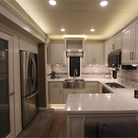 Custom RV kitchen from New Horizons in all white with stainless steel farm sink and large pantry